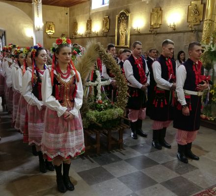 chłopcy i dziewczęta w strojach krakowskich stojący w kościele przy wieńcach dożynkowych